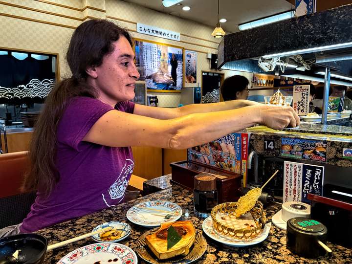 Maria grabbing a dessert order off of the conveyor belt